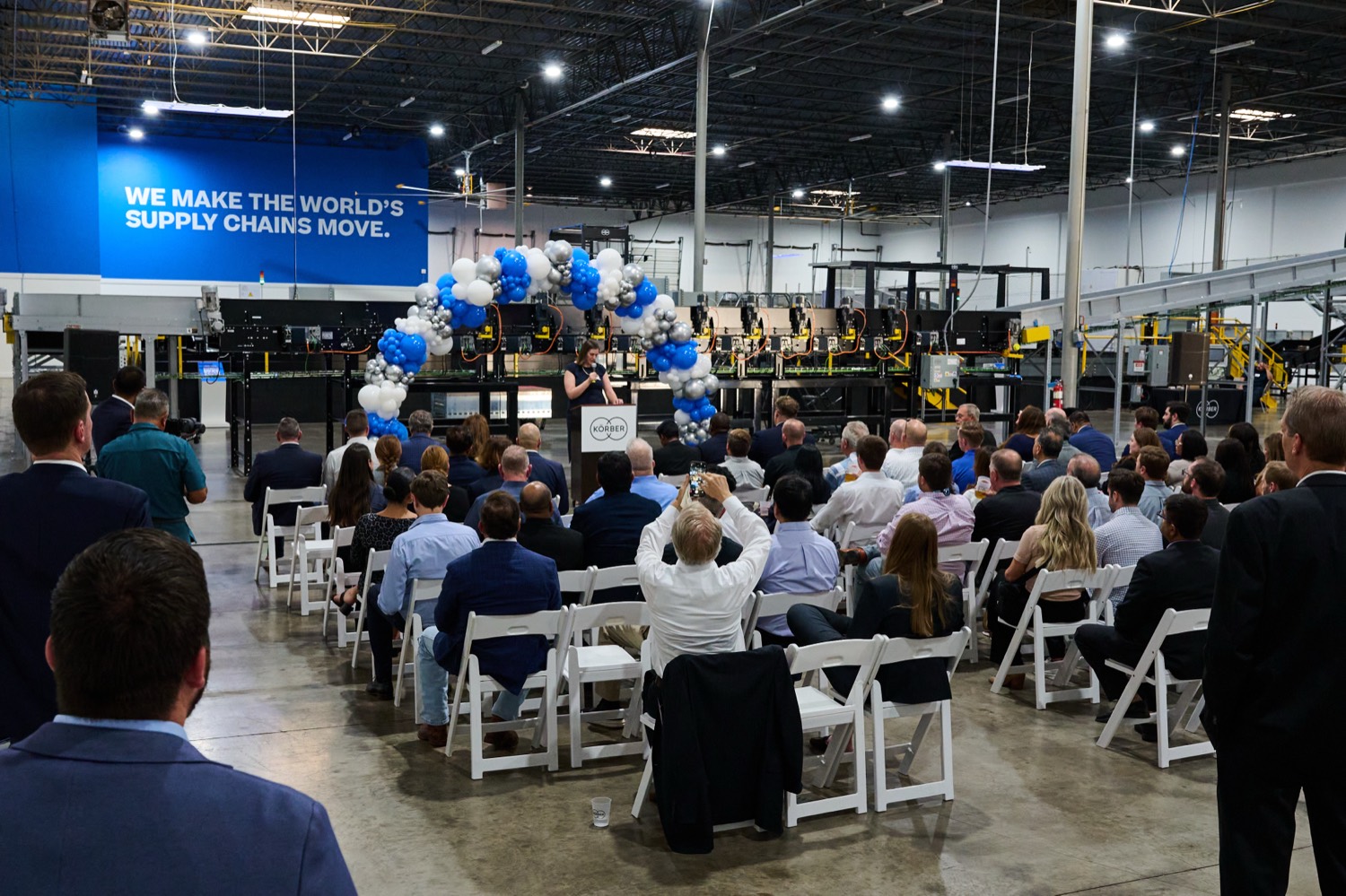 A speaker addresses a seated audience at a corporate launch event produced by CM Promotions